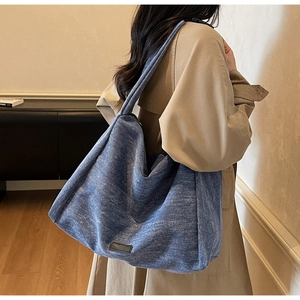 Close-up of a large blue canvas tote bag featuring a minimalist grey label and rich texture