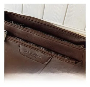 Detail showing the multi-zipper top closure and fine stitching of dark brown crossbody bag
