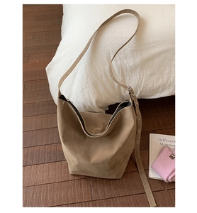 Close-up of brown suede shoulder bag showing metal adjustment holes and black zipper