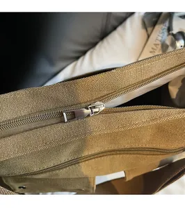 Close-up of smooth metal zipper and durable canvas texture on a khaki crossbody bag
