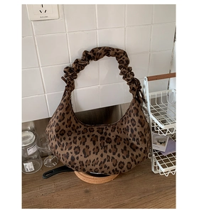 Detail of leopard print tote bag with a unique scrunchie handle and plush fabric texture