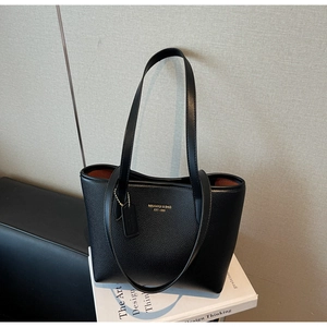 Détail du cabas en cuir grainé noir avec logo doré et doublure contrastée