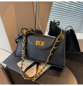 Vue détaillée d'un sac noir élégant avec fermoir doré et bandoulière en chaîne chic