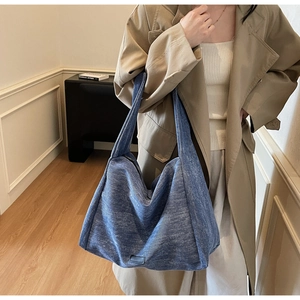 Detail of blue denim hobo tote bag showing large capacity and textured fabric on shoulder