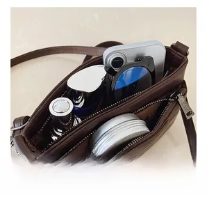 Detail view of brown faux leather crossbody bag showing dual zipper compartments and interior capacity