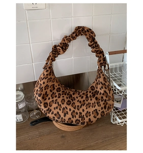 Detail of leopard print crescent bag with distinctive black and brown spots and scrunchie handle