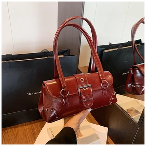 Gros plan sur un sac baguette en cuir ciré rouge foncé avec boucles et rivets argentés