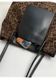 Detail of leopard print tote bag with black leather front pocket and spacious interior