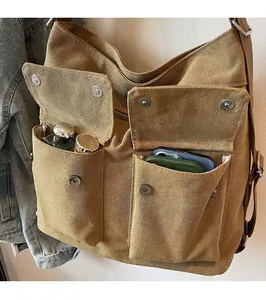 Close-up of khaki canvas tote bag featuring functional front pockets and metallic buttons