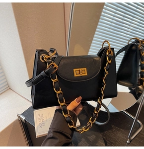 Détail d'un sac à main trapèze noir avec fermoir doré et bandoulière en chaîne tressée