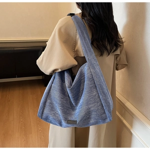 Detail of light blue denim texture tote bag with adjustable black strap and buckle