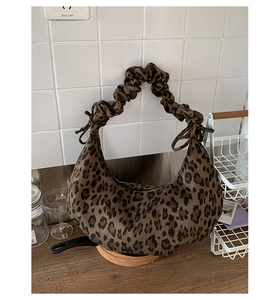 Detail of hobo bag featuring leopard print fabric and a ruched drawstring handle