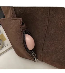 Detail of dark brown suede tote bag featuring an external zipper pocket and silver hardware
