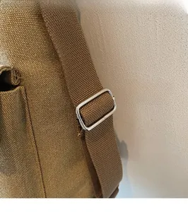 Close-up of adjustable woven shoulder strap with silver metal buckle on brown canvas tote