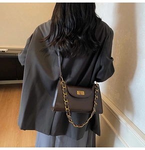Détail du sac à bandoulière en cuir marron foncé avec fermoir doré et bandoulière chaîne