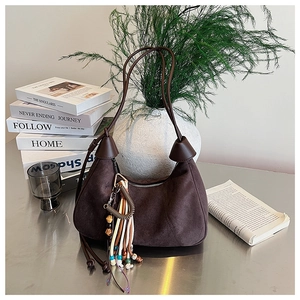 Détail du sac à main en daim marron avec pompon en perles colorées et fines lanières