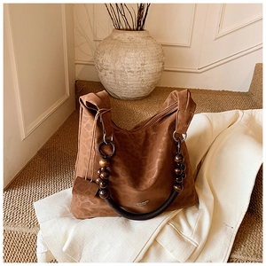 Détail du sac hobo avec gaufrage léopard, poignée en bois et texture daim souple