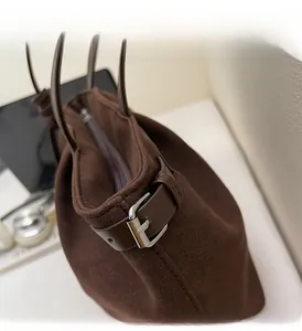 Detail of dark brown matte tote bag showing silver metal buckle and zipper closure