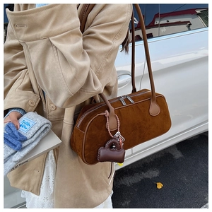 Detail of caramel suede Boston bag with silver zipper and mini leather charm pendant