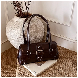 Détail du sac vintage en cuir ciré avec boucles argentées et rivets sur un tapis tressé