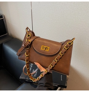 Détail d'un sac à main vintage en cuir marron avec chaîne dorée et fermoir pivotant