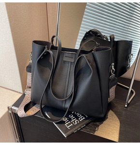 Close-up of black lychee grain leather tote bag with a decorative woven wide shoulder strap