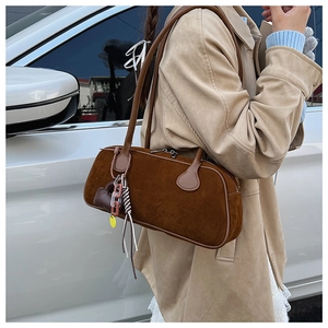 Detail of a brown suede boston bag with heart charms and acrylic chain tassels