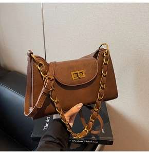 Détail d'un sac à main vintage marron avec fermoir tournant doré et bandoulière chaîne
