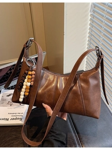 Vintage brown leather hobo bag with adjustable strap and decorative beaded charm