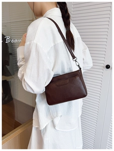 Detailed macro view of dark brown PU leather crossbody bag with silver metal hooks