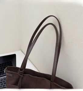 Detailed close-up of durable leather handles and fine stitching on dark brown tote bag