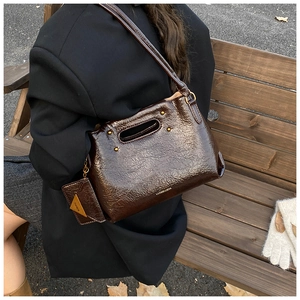 Detail of dark brown oil wax leather handbag with small triangular charm and shoulder strap