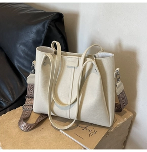 Close-up of cream white lychee leather tote bag with geometric pattern wide shoulder strap