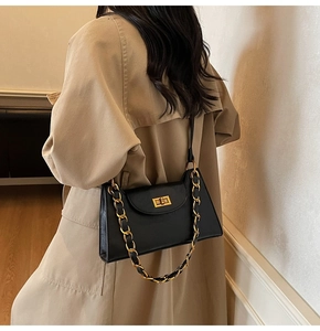 Détail d'un sac bandoulière noir structuré avec chaîne dorée et fermoir rotatif