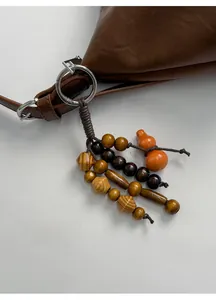 Detail eines handgefertigten Holzperlenanhängers mit orangefarbenem Kürbis an der Tasche