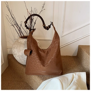 Détail du sac hobo léopard avec poignée en perles de bois et logo de marque visible