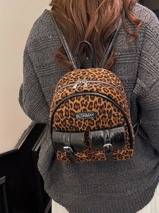 Sac à dos léopard tendance avec bordures noires brillantes porté par un mannequin en automne