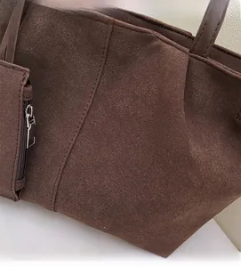 Detail of soft dark brown suede tote bag featuring a side zipper pocket and fine stitching