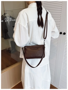 Close-up of brown PU leather crossbody bag with silver hardware and adjustable strap