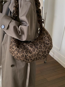 Chic leopard print crescent shoulder bag with pleated strap shown on a female model