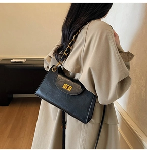 Détail du sac à chaîne noir avec fermoir doré rotatif et texture cuir froissé