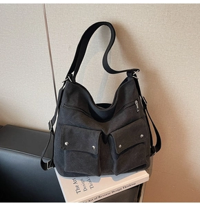 Detail einer schwarzen Canvas-Tasche mit Doppelklappentaschen und Silbernieten