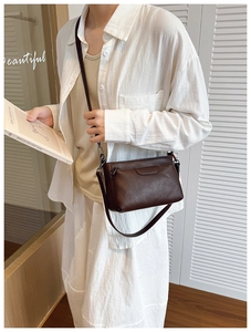 Close-up of deep brown crossbody bag with smooth leather texture and metal buckles
