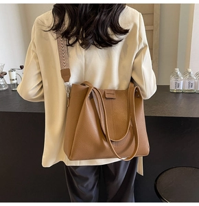 Detail view of brown pebbled leather tote bag with a wide geometric patterned shoulder strap