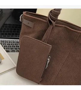 Close-up of brown suede tote bag with detachable mini pouch and office accessories