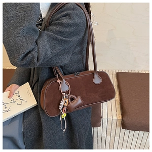 Detail of walnut brown frosted leather bowling bag showing suede texture and heart charm