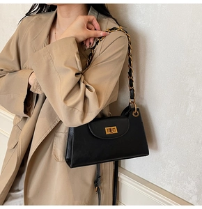 Détail d'un sac à chaîne noir avec fermoir doré porté par un mannequin en trench beige