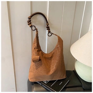 Détail du sac à bandoulière léopard avec poignée en perles de bois vintage sur un livre