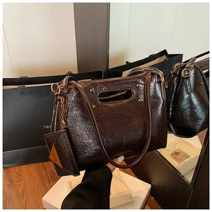 Detail of dark brown oil-wax leather handbag with golden chain and small coin purse