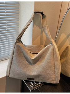Minimalist sand beige canvas tote bag with adjustable black buckle strap and side label